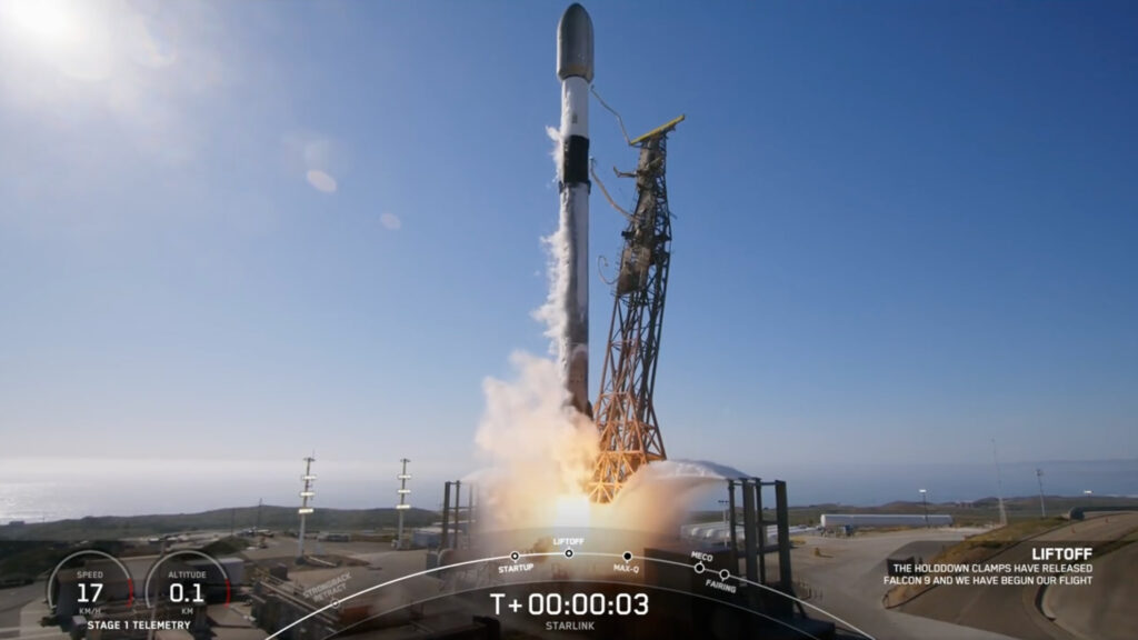 a black and white rocket rises off a launch pad into a blue sky